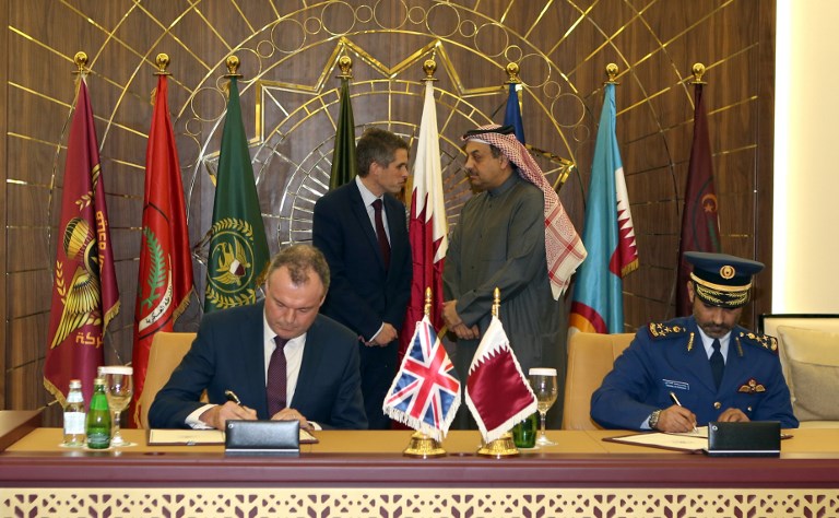 وزير الدفاع القطري خالد العطية ونظيره البريطاني غيفن ويليامسن يتبادلان الحديث خلال عملية توقيع الإتفاقية العسكرية بين البلدين في الدوحة (AFP)