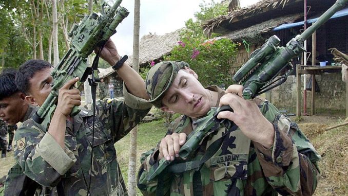 يقوم الرقيب نيل استرادا (يمين) في القوات الخاصة بالجيش الأميركي بإشارة إلى نظيره الفلبيني الرقيب أغوستين سوليزا (يسار) على M4A1-Carabine الأمريكية الصنع ، وهو السلاح المعتاد للقوات الخاصة الأميركية، في مقر بيرجاد الثالث عشر للجيش الفلبيني في تابياوان في جزيرة باسيلان في 20 فبراير 2002 (AFP) بندقية M4A1
