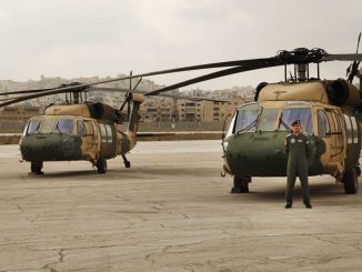 القائد طارق المغيرة يقف أمام طائرتي هليكوبتر من طراز UH-60A، تعرفان باسم "بلاك هوك"، سلّمتها الولايات المتحدة للأردن في مطار ماركا في عمان، في 3 آذار/مارس 2016 (AP)