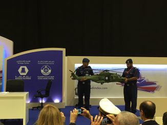 عنصران من القوات الجوية الأميرية القطرية يحملان نموذج عن مروحية NH90 المخصصة لقطر خلال حفل توقيع الاتفاق (الأمن والدفاع العربي)