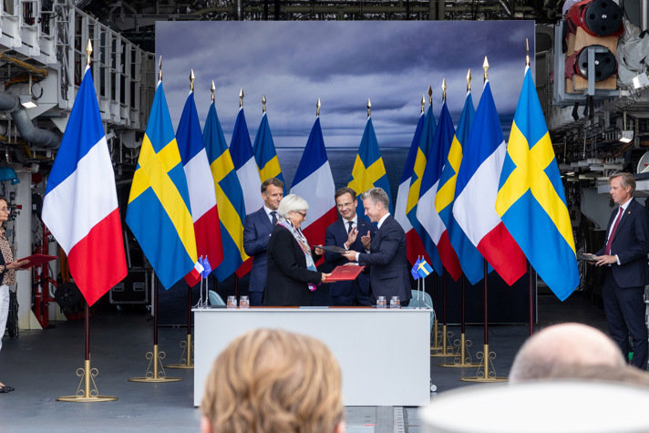 Försvarsminister Pål Jonson och franska försvarsminister Catherine Vautrin signerar avtal framför flaggor. Bakom står Statsminister Ulf Kristersson och President Emmanuel Macron.